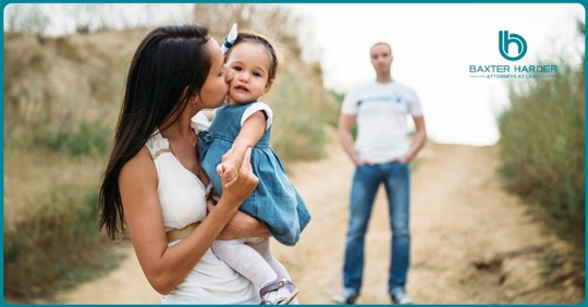 woman holding baby man in background