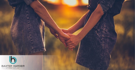 two women wearing matching dresses holding hands in a field