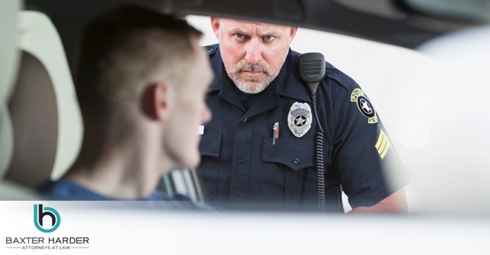 police officer looking into car at male driver