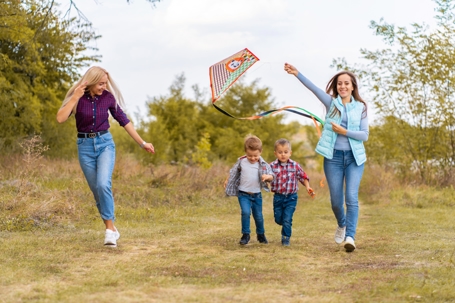 Happy non traditional family of two young mother and their kids launch a kite on nature at sunset